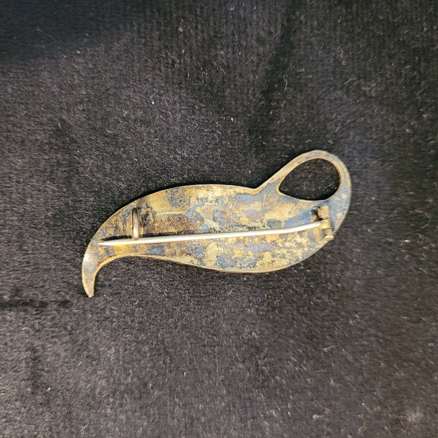 Rückseite einer antiken Brosche in Form eines stilisierten Blattes. Zeigt Patina und Gebrauchsspuren. Besteht aus Metall mit Nadel und Verschlussmechanismus.
