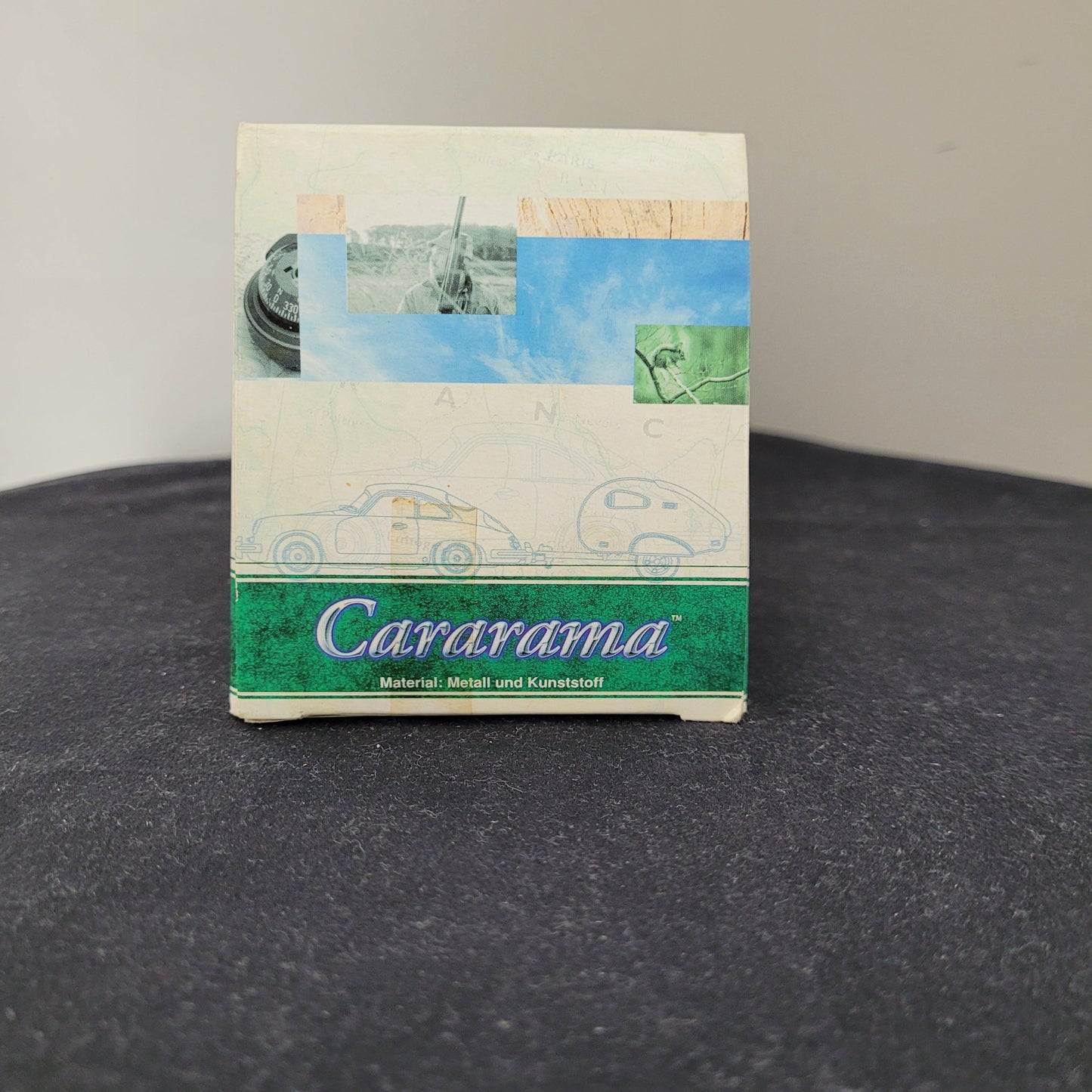Seitenansicht der Originalverpackung des Carararama – Hongwell – VW Beetle Modellautos 1:43 mit stylisiertem grünem Carararama-Logo, Materialangabe Metall und Kunststoff sowie Illustrationen von Reifen, Landschaft und Fahrzeugskizzen