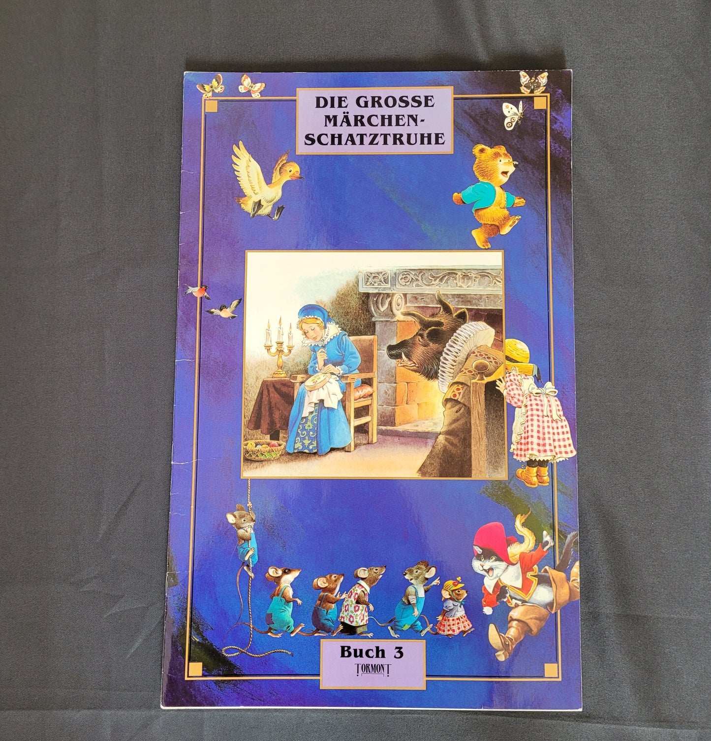 Vintage Cover des Kinderbuchs „Die große Märchenschatztruhe – Buch 3“ mit fantasievollen Illustrationen klassischer Märchenfiguren wie Rotkäppchen, einem sprechenden Bären und fliegenden Gänsen auf violettem Hintergrund mit Sternen. Das nostalgische Design und die liebevoll gezeichneten Szenen machen dieses Vintage-Märchenbuch zu einem charmanten Sammlerstück für Liebhaber traditioneller Kinderliteratur und märchenhafter Geschichten.
