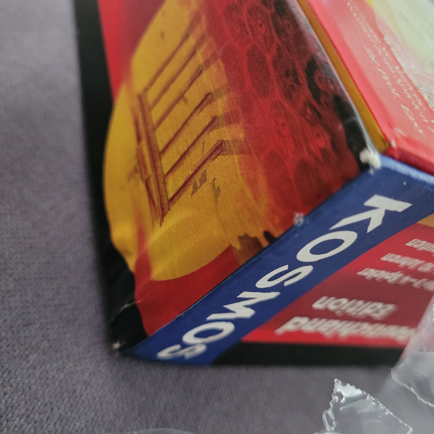 Detailansicht Die Siedler von Catan – Deutschland Edition Brettspiel von Kosmos, EAN 4002051693015, mit KOSMOS‑Logo, rotem und gelbem Coverdesign, Brandenburg‑Tor‑Illustration und leichter Beschädigung an der Verpackung