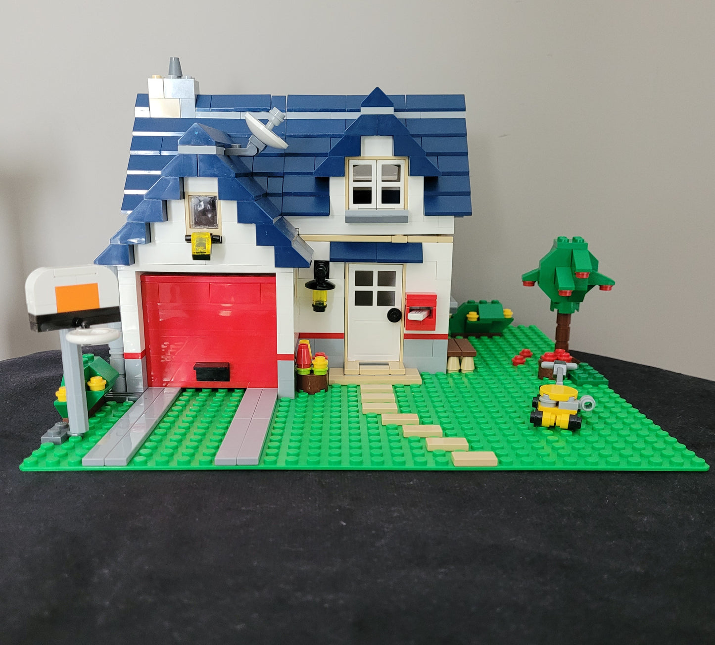 Das LEGO Creator Modell 5891 - Haus mit Garage – detailreiches Einfamilienhaus mit blauen Dachziegeln, rotem Garagentor und liebevoll gestalteter Umgebung inklusive Baum, Briefkasten und Rasenmäher. Perfektes Set für LEGO-Fans und Sammler! EAN: 5702014600546.
