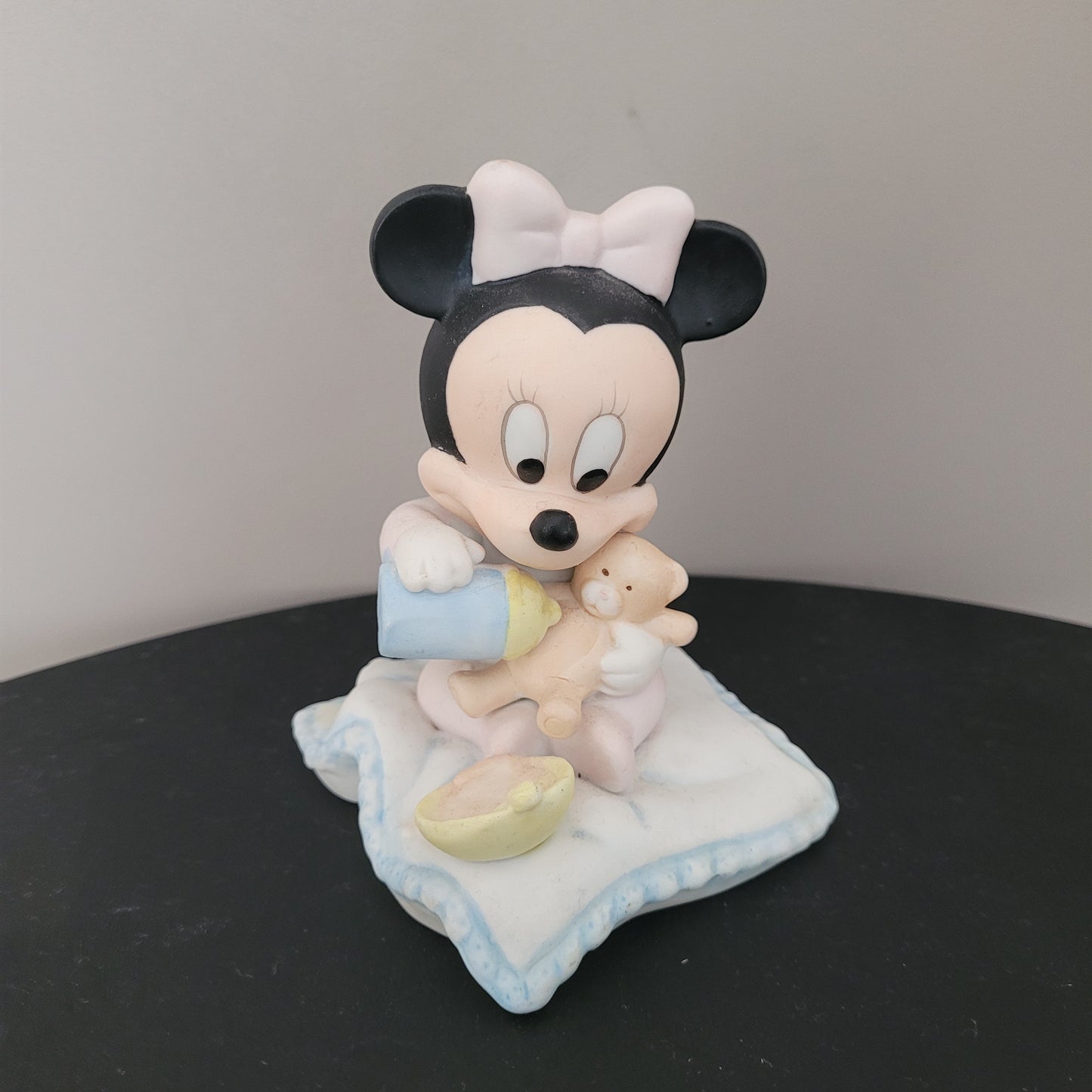 Minnie Mouse Figur vom Hersteller Goebel Hauptfoto mit einem Teddybär und Trinkflasche in der Hand.