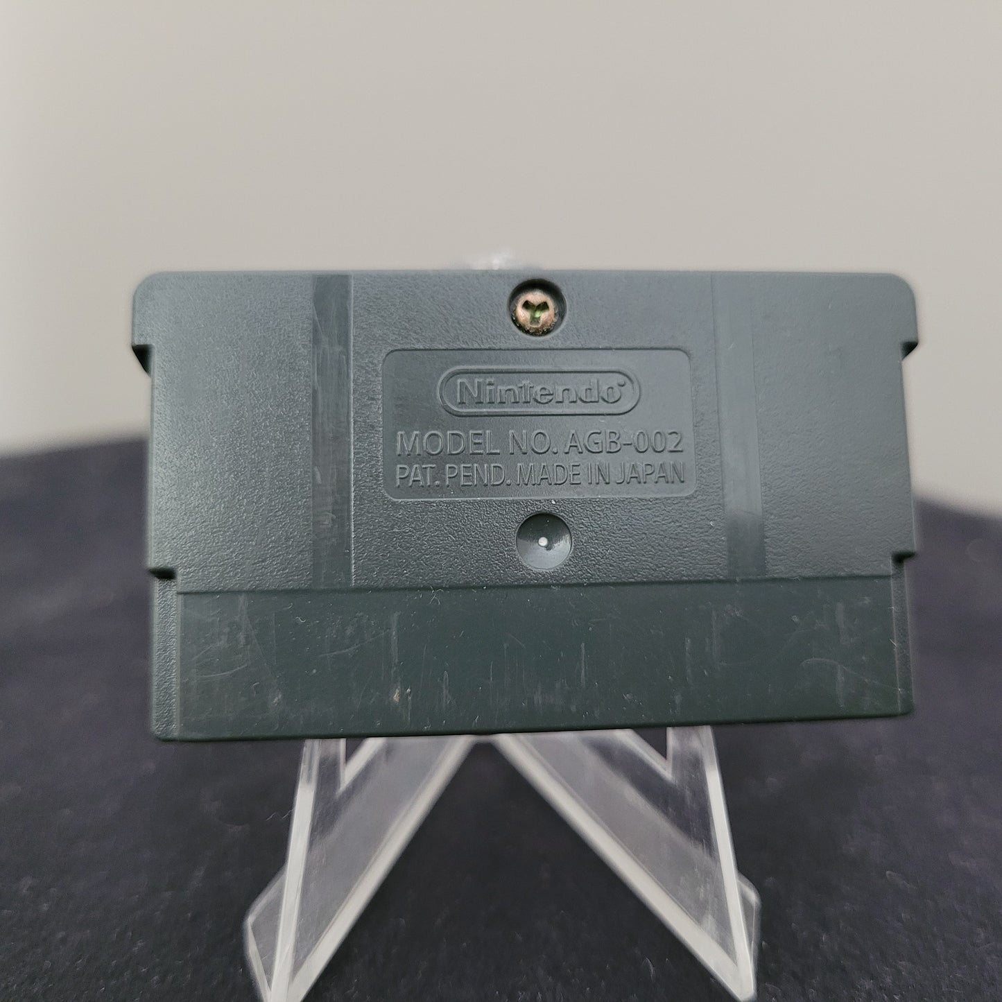 Die Rückseite des Nintendo Game Boy Advance Spielmoduls Final Fantasy Tactics Advance, Modellnummer AGB-002, auf einem transparenten Ständer präsentiert. Der Schriftzug Nintendo sowie die Kennzeichnung PAT. PEND. MADE IN JAPAN sind deutlich sichtbar. Dieses geprüfte und funktionstüchtige Nintendo-Spiel ist ein Muss für Sammler und Retro-Gaming-Fans.