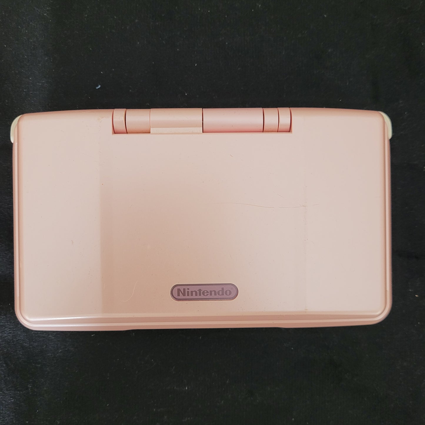 Draufsicht der Nintendo DS Pink Model No NTR-001 Handheld Konsole, offen auf schwarzem Untergrund liegend. Perfekte Retro-Konsole für Sammler und Gaming-Fans!
