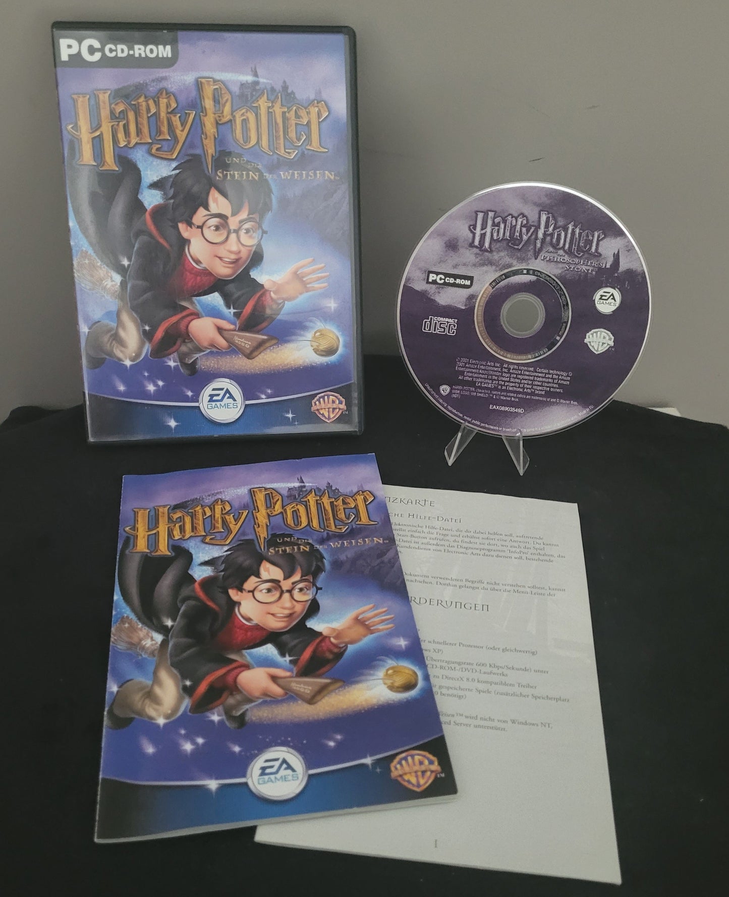 Zu sehen ist das PC von EA Sports Harry Potter und der Stein der Weisen, auf schwarzem Unter- und grauem Hintergrund.