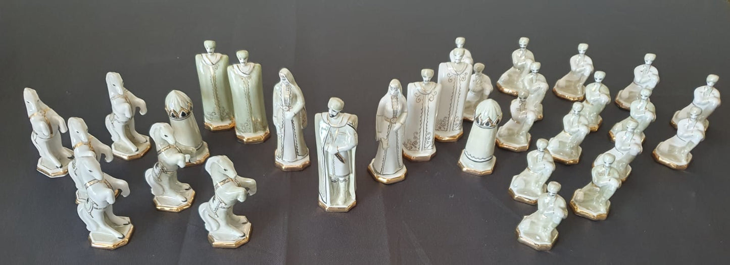 Das Bild zeigt die Vorderseite der Vintage-Schachfiguren aus Kislovodsk, kunstvoll arrangiert auf einem schwarzen Untergrund. Im Hintergrund hebt sich eine weiße Fläche ab, die die feinen Porzellandetails und die Farbgebung der Figuren besonders betont.