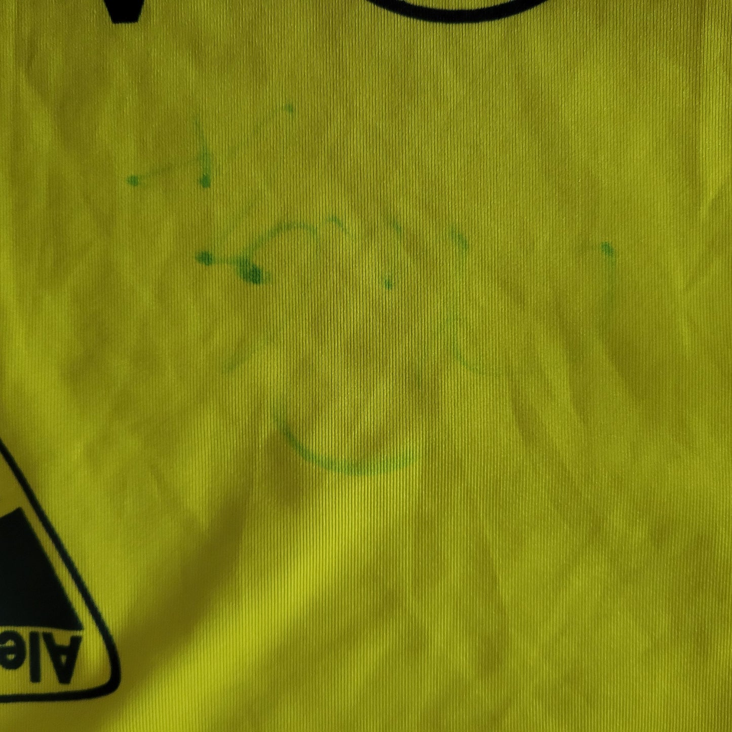 Unterschrift bzw. Signatur eines Spielers des TSV Alemannia Aachen aus der Bundesliga Saison 2006/2007, welche kaum noch erkennbar ist ,ist zu sehen. In grün und der Hintergrund ist gelb.