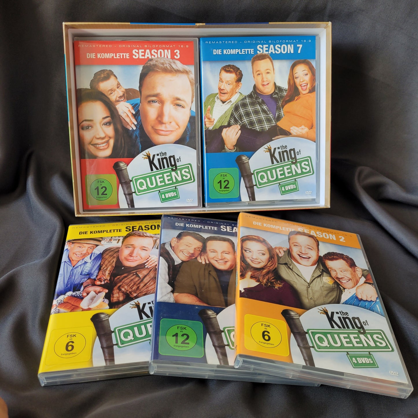 he King of Queens DVD-Box mit Staffeln 2, 3, 5, 6 und 7, farbige Hüllen mit Altersfreigaben, Cover mit Doug, Carrie und Arthur, Sammleredition der Kult-Sitcom