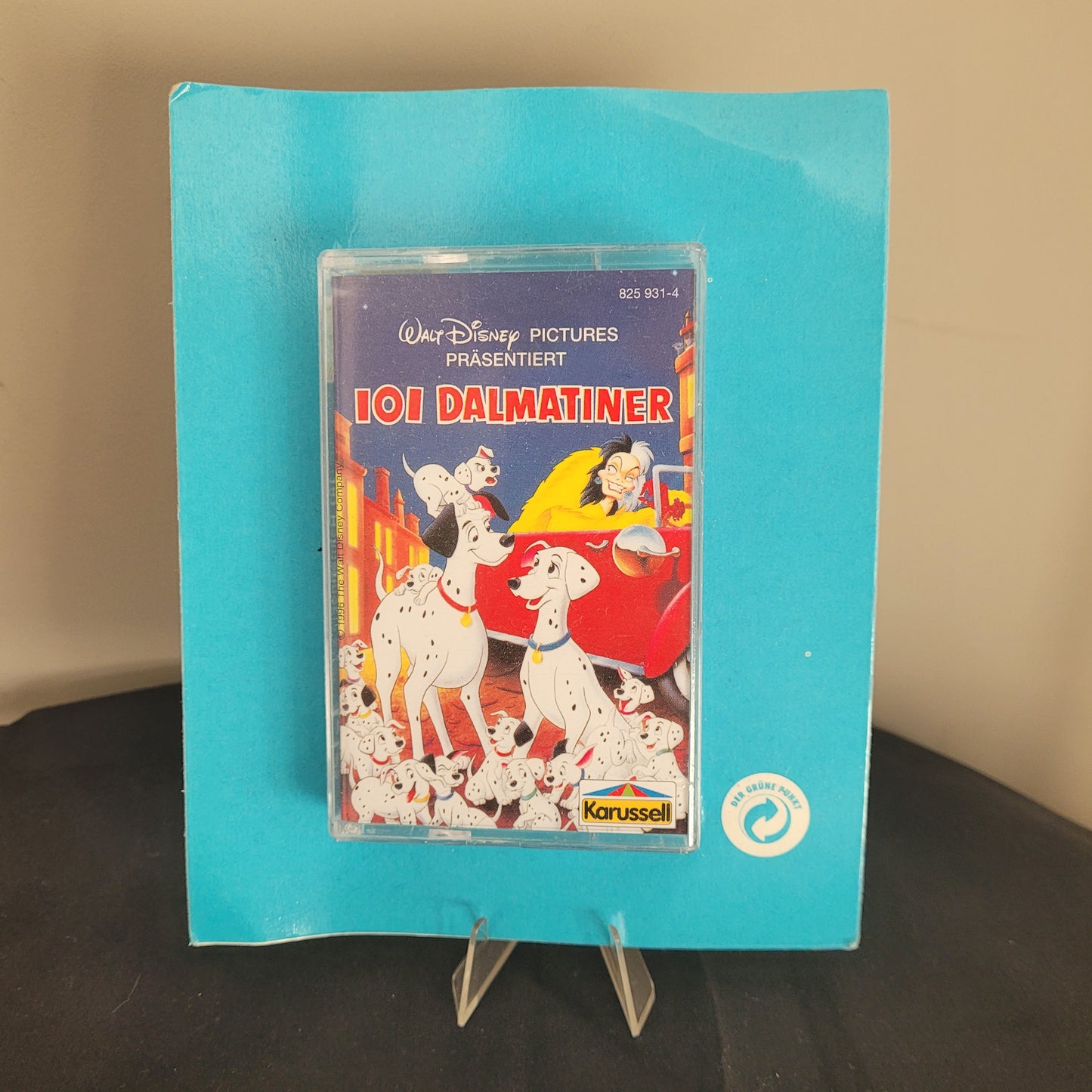 Das Bild zeigt eine Kassette des Films \"101 Dalmatiner\" von Walt Disney Pictures, präsentiert von Karussell. Die Kassette ist in einer blauen Verpackung und zeigt auf dem Cover mehrere Dalmatinerhunde und die Figur Cruella de Vil in einem roten Auto. Die Kassette ist in einem durchsichtigen Kunststoffgehäuse verpackt. Oben rechts auf der Verpackung befindet sich das Karussell-Logo.