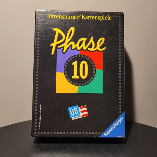 Vorderansicht der schwarzen Phase 10 Spieleverpackung von Ravensburger mit dem farbigen Logo und US-Bestseller-Abzeichen auf dunklem Untergrund.