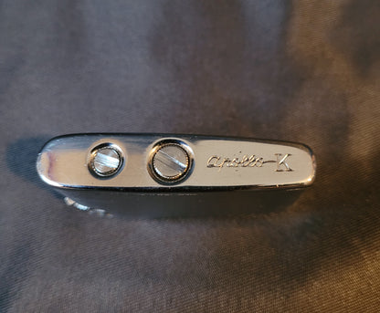 Apollo-K Feuerzeug Vintage, silberfarben, Unterseite mit Gasnachfüllöffnung, Hintergrund schwarz, kompaktes Sammler-Feuerzeug.