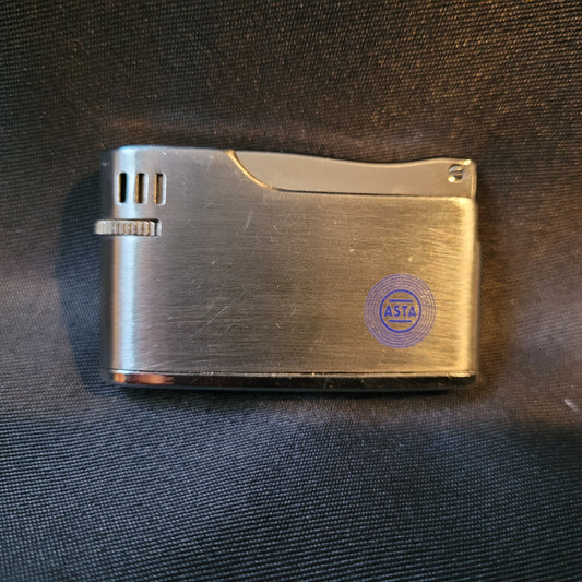 Apollo-K Feuerzeug Vintage, silberfarben, Vorderseite mit blau graviertem ASTA Logo, Hintergrund schwarz, kompaktes Sammlerstück 5,5 × 3 × 1 cm.