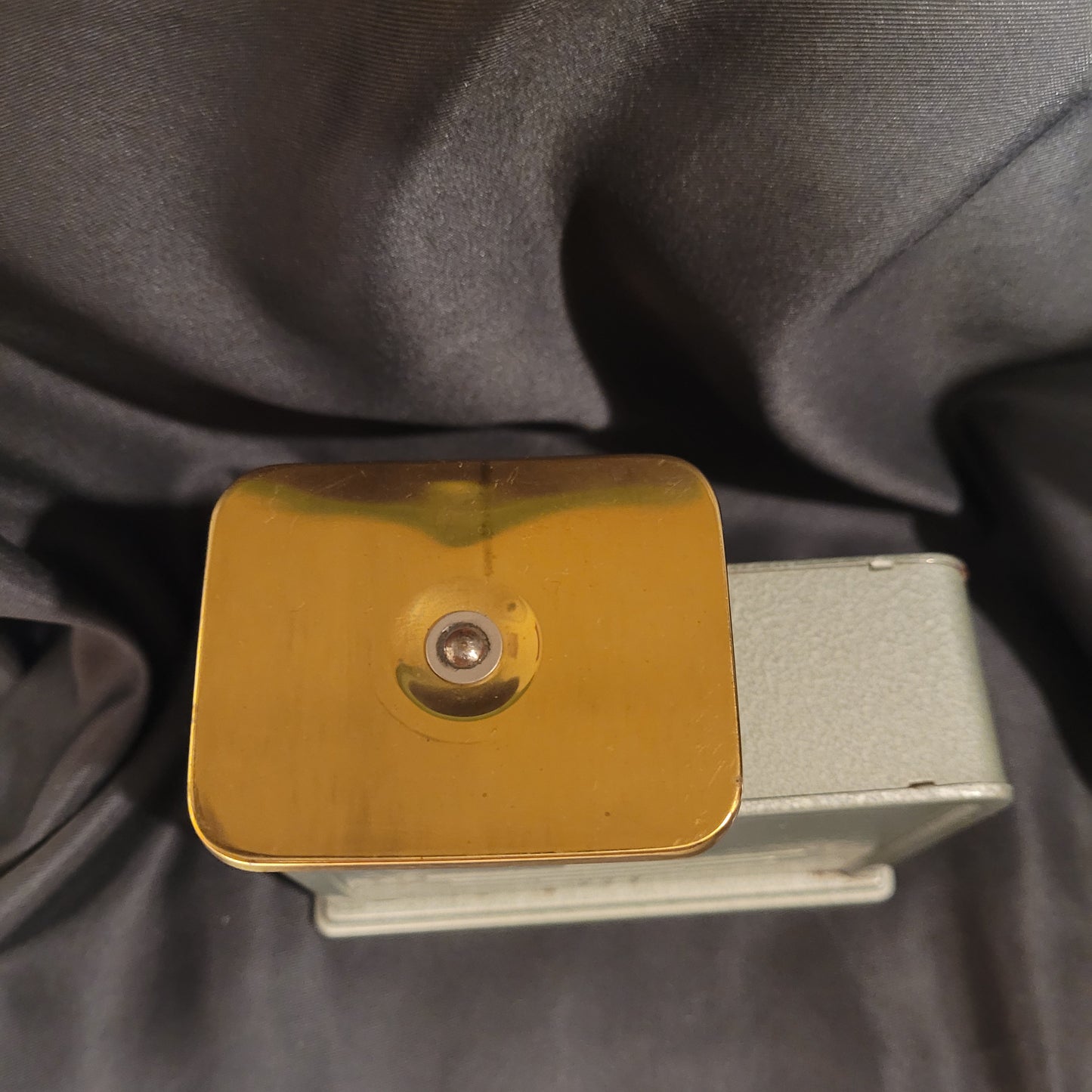 Arca 500 Briefwaage Küchenwaage Mid Century Vintage, Oberseite mit Wiegefläche in goldener Farbe, leicht grünlich oder silbern schimmernd, schwarzer Hintergrund.