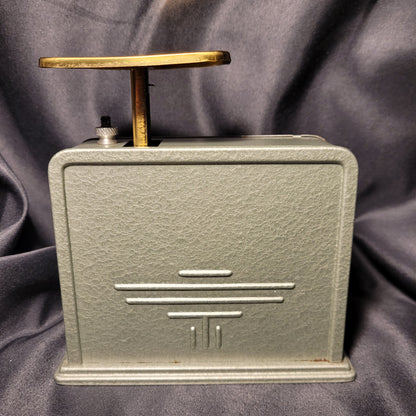 Arca 500 Briefwaage Küchenwaage Mid Century Vintage, Rückansicht, Metallgehäuse mit Hammerschlag-Optik, leicht grünlich oder silbern schimmernd, schwarzer Hintergrund. Ein Logo oder Zeichen ist sichtbar.