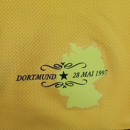 Es ist "DORTMUND 29 MAI 1997" zu lesen. usätzlich kann man die geographische Darstellung von Deutschland sehen. Zwsichen Dortmund und 28 Mai 1997 ist ein schwarzer Stern. Das Ganze ist ein Teil des Borussia Dortmund BVB Vintage Trikots 2007-2008 Größe L – Nike Fit Dry