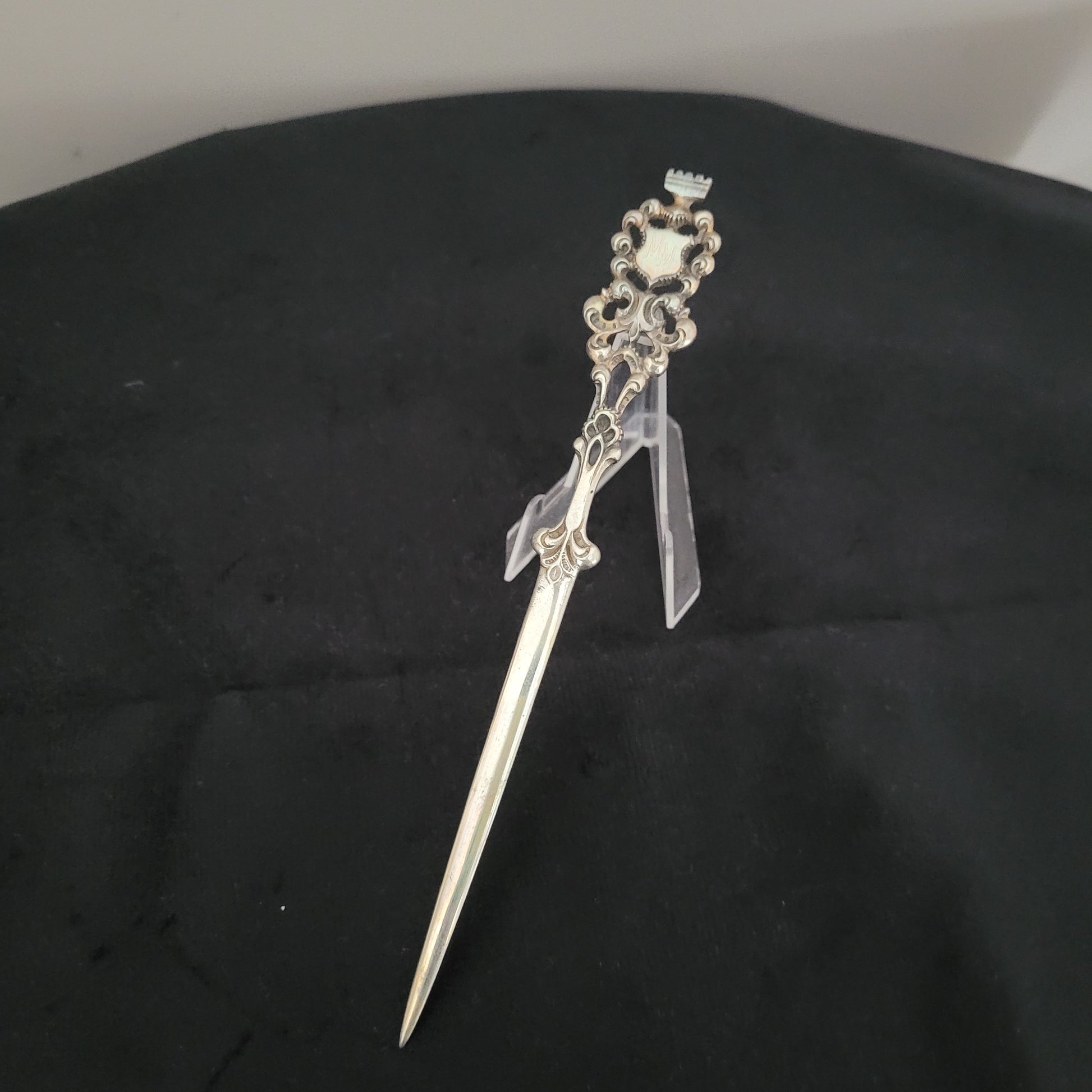 Antiker, kunstvoll verzierter Brieföffner mit filigranen Details und spitz zulaufender Klinge, auf schwarzem Hintergrund präsentiert. Ideal für Sammler und Liebhaber historischer Schreibwaren.