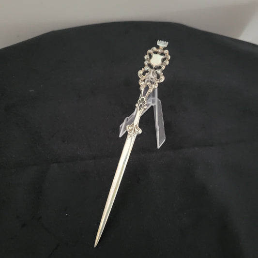 Antiker, kunstvoll verzierter Brieföffner mit filigranen Details und spitz zulaufender Klinge, auf schwarzem Hintergrund präsentiert. Ideal für Sammler und Liebhaber historischer Schreibwaren.