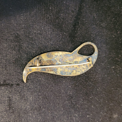 Rückseite einer antiken Brosche in Form eines stilisierten Blattes. Zeigt Patina und Gebrauchsspuren. Besteht aus Metall mit Nadel und Verschlussmechanismus.