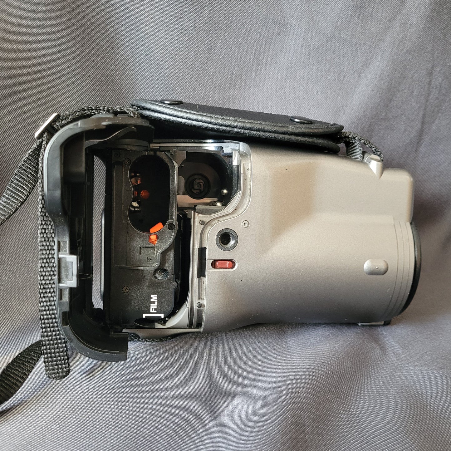 Seitenansicht Canon Epoca Kompaktkamera 35‑105mm Auto Zoom mit geöffnetem Batteriefach und sichtbarem SD‑Kartenslot mit Wi‑Fi‑Funktion, Vintage Kamera mit Trageriemen