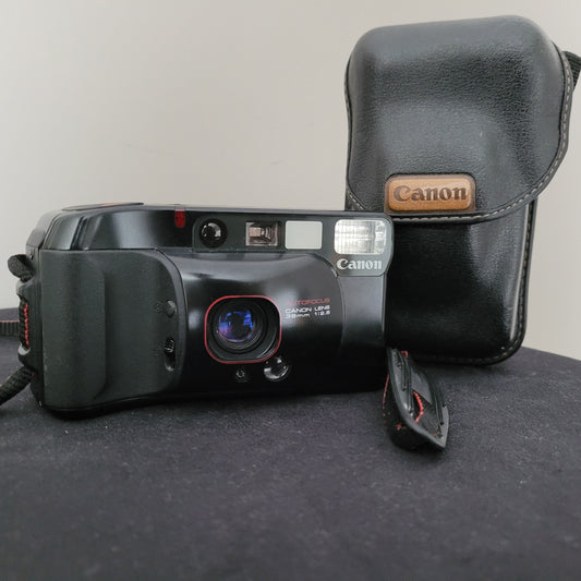 Canon Sure Shot Supreme 35mm Analogkamera mit Autofokus und 38mm f/2.8 Objektiv, präsentiert mit originaler schwarzen Leder-Schutztasche – ideal für Liebhaber klassischer Fotografie und Vintage-Kameras.