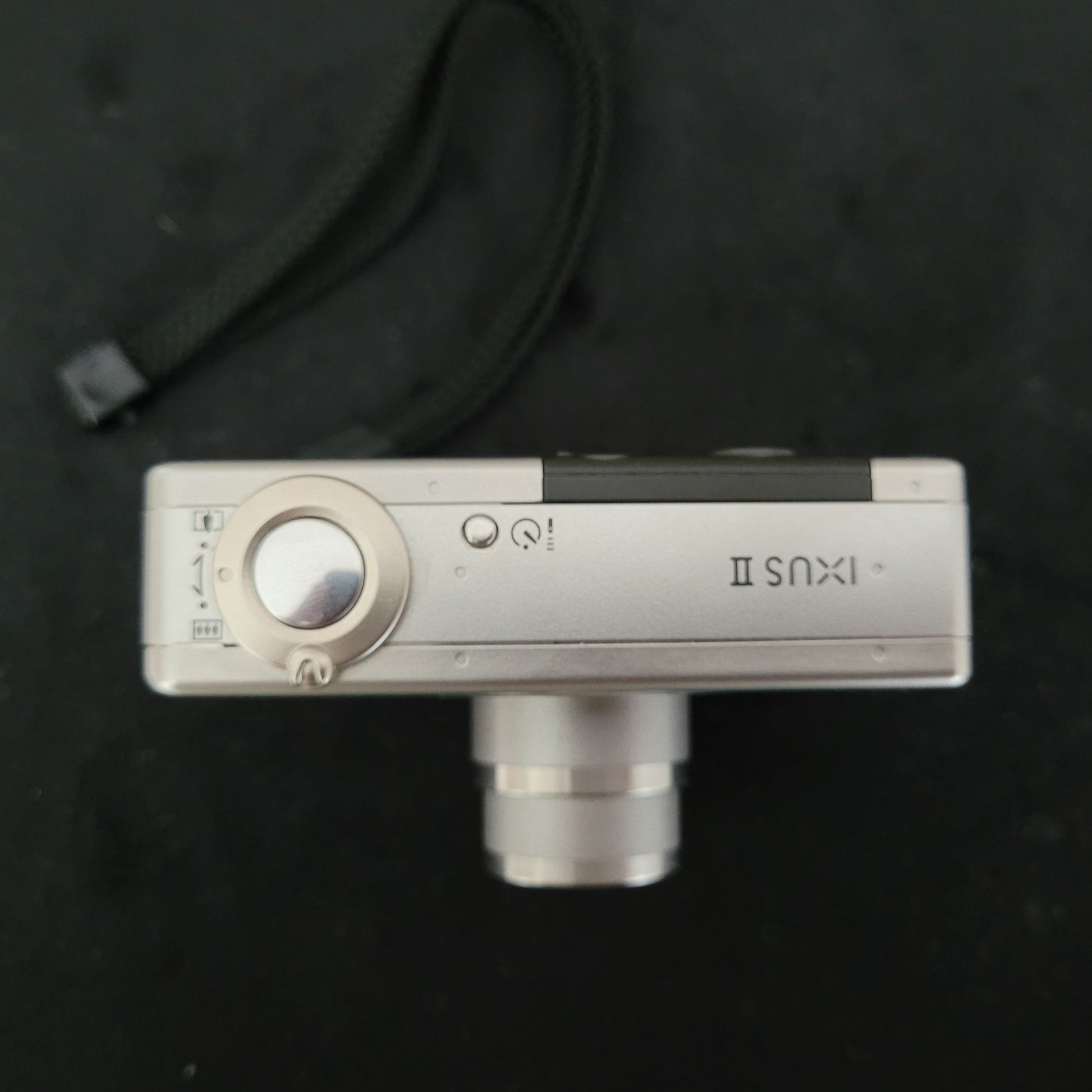 Obenansicht der Canon Vintage Kamera Ixus II S mit ausgefahrenem Objektiv, sichtbarem Auslöser und Zoomhebel – klassische Kompaktkamera im Retro-Design für Sammler und Fans nostalgischer Canon-Technik.