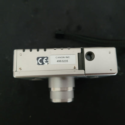 Untenansicht der Canon Vintage Kamera Ixus II S mit sichtbarem Batteriefach,CE-Kennzeichen, Seriennummer und Stativgewinde – kompakte Retro-Digitalkamera für Sammler und Fans klassischer Canon Vintage Technik.