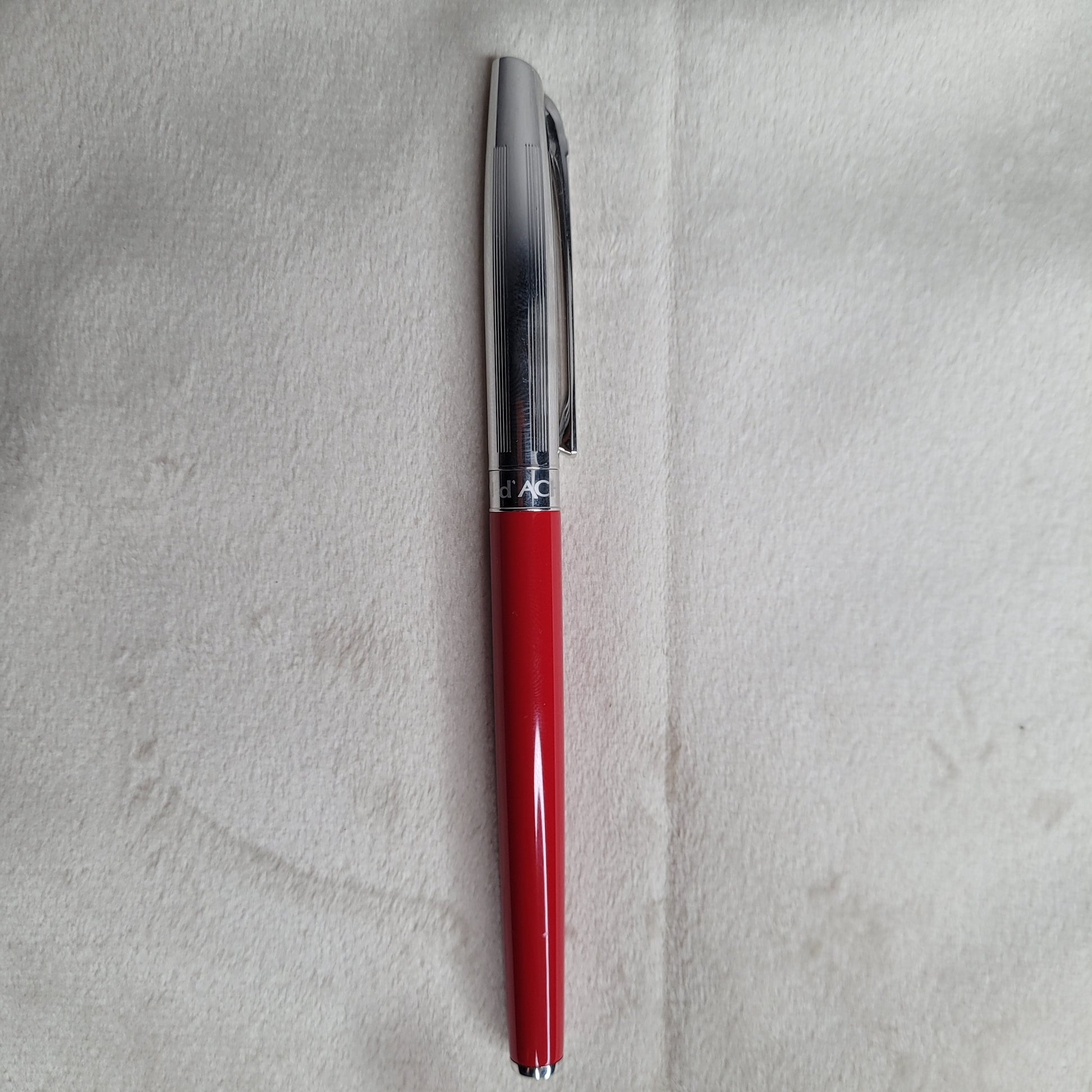 Caran d'Ache Kugelschreiber - Swiss Made, rotes Gehäuse, silberne Kappe auf hellem Hintergrund.
