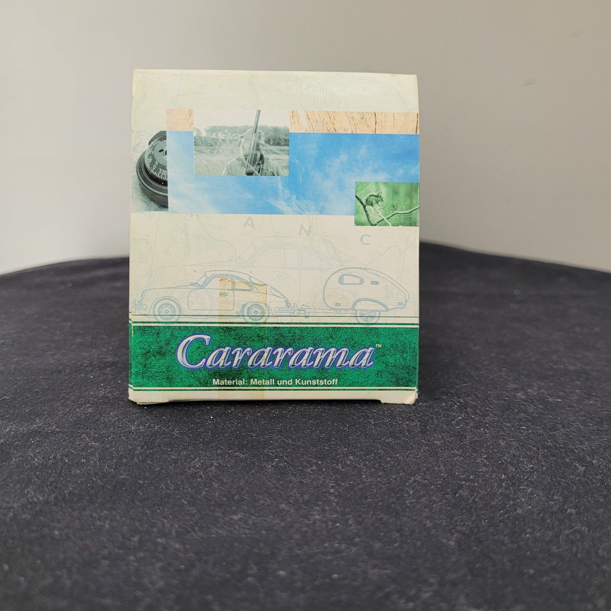 Seitenansicht der Originalverpackung des Carararama – Hongwell – VW Beetle Modellautos 1:43 mit stylisiertem grünem Carararama-Logo, Materialangabe Metall und Kunststoff sowie Illustrationen von Reifen, Landschaft und Fahrzeugskizzen