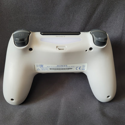 Rückseite eines Controller "Camouflage" – PlayStation 4 / PS4 – DualShock 4 – Original Sony in grau‑schwarz‑weißem Tarnmuster, mit sichtbaren L1‑ und R1‑Schultertasten, Lightbar, Micro‑USB‑Ladeanschluss und Modellaufkleber, liegend auf dunkler Stoffoberfläche. EAN 0711719453512 / Modell CUH-ZCT1E