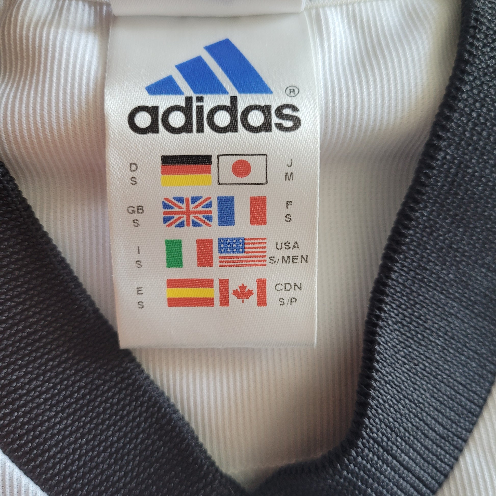 Deutschland  DFB Vintage Trikot 2002 - Größe S - Es  ist Das Logo von Adidas und verschieden Flaggen mit Kleidungsgrößen zu sehen.