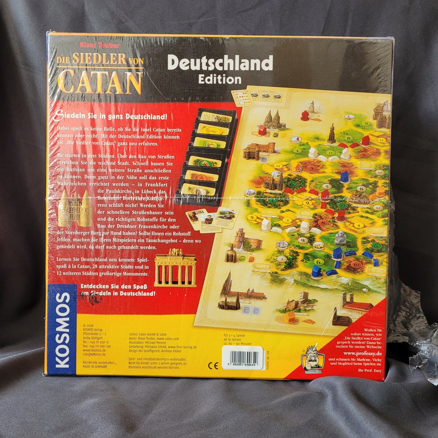 Rückseite Die Siedler von Catan – Deutschland Edition Brettspiel von Kosmos, EAN 4002051693015, mit Deutschlandkarte, Spielmaterial, Wahrzeichen‑Miniaturen und Beschreibung des Strategiespiels von Klaus Teuber