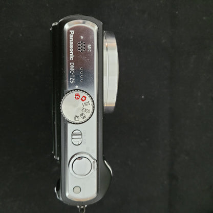 Draufansicht der Panasonic Lumix DMC-TZ5 Digitalkamera liegt auf einem schwarzen Untergrund. Es sind verschiedene Bezeichnungen zu lesen wie MIC oder DMC-TZ5.