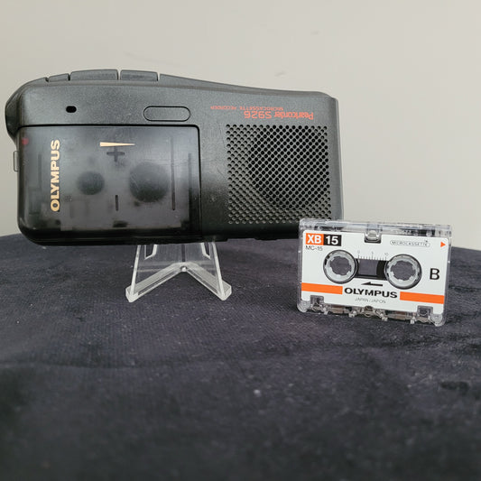 Olympus Pearlcorder S926 Diktiergerät – Vintage-Elektronik mit Mikrokassette Das Bild zeigt das Olympus Pearlcorder S926 Diktiergerät, ein klassisches Modell aus dem Bereich der Vintage-Elektronik. Das kompakte Gerät besitzt ein silberfarbenes Gehäuse mit funktionalen Bedienelementen und einem integrierten Mikrofon. Die Aufnahme erfolgt über Mikrokassetten, die das typische analoge Diktier-Erlebnis bieten.