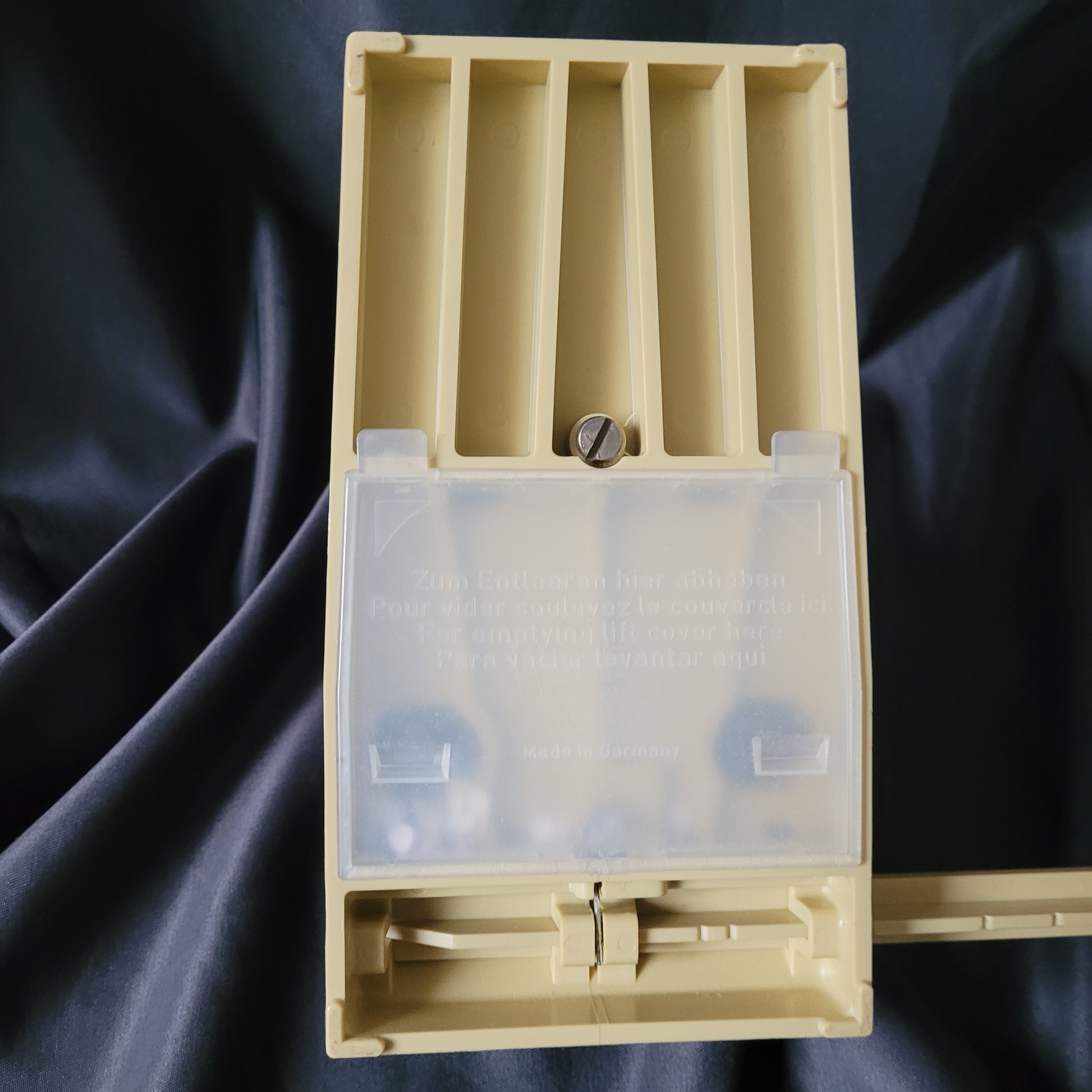 Rückseite des ELBA 49480 Büro Vintage Registraturlochers mit massivem Metallgehäuse und beige-farbenem Kunststoffunterteil auf dunklem Stoffhintergrund.