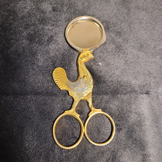 Vergoldete Vintage Eierschere mit kunstvoll gestaltetem Griff in Form eines Vogels, detaillierte Verzierungen, auf dunklem Hintergrund