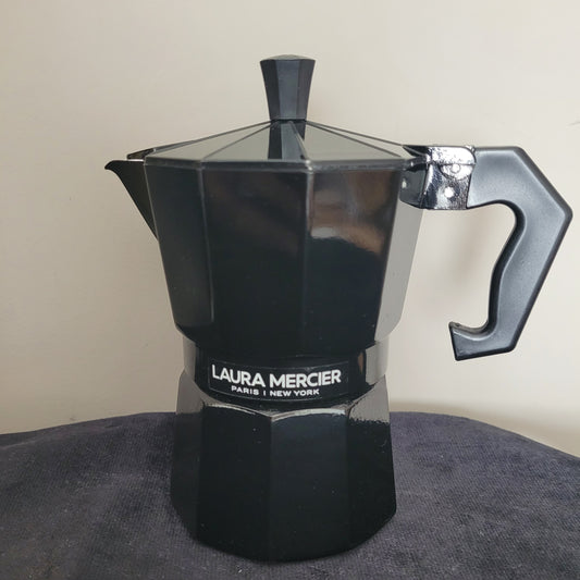 Eleganter Espressokocher Laura Mercier Design in Schwarz mit sechseckiger Form und hochwertigem Finish. Die stilvolle Kanne trägt die Markensignatur Laura Mercier Paris | New York und steht auf einer dunklen Oberfläche mit hellem Hintergrund. Perfekte Kombination aus modernem Design und Kaffeegenuss für echte Liebhaber.