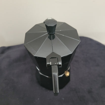 Rückansicht des eleganten Espressokochers Laura Mercier Design in Schwarz mit stilvoller sechseckiger Form und glänzendem Finish. Der schwarze Griff und Deckel unterstreichen das edle Design, während die hochwertige Verarbeitung für Langlebigkeit und optimalen Kaffeegenuss sorgt. Perfekt für stilvolle Espressozubereitung mit Laura Mercier Qualität.