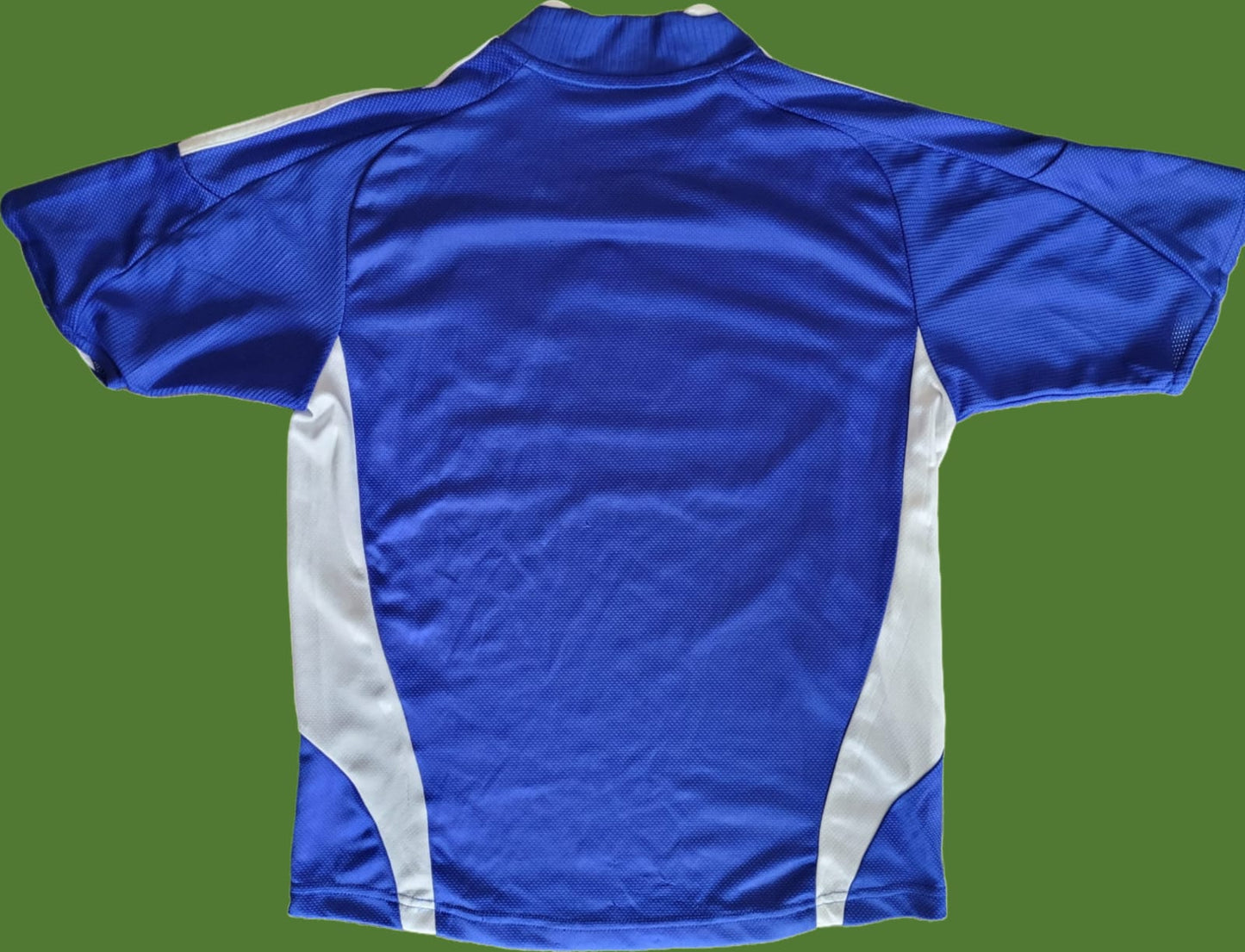 Das Bild zeigt die Rückseite eines FC Schalke 04 Vintage Trikots in Größe S, vermutlich aus der Saison 2006/07 oder 2007/08. Das Trikot ist vollständig in Königsblau gehalten, mit weißen Seiteneinsätzen unter den Ärmeln. Auf der Rückseite sind keine Rückennummern, Spielernamen oder Sponsorenlogos zu sehen, was für ein unbeflocktes Trikot typisch ist. Der atmungsaktive Stoff und das klassische Design spiegeln den zeittypischen Stil der damaligen Spielkleidung wider.