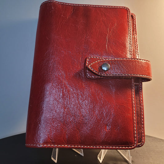 Eleganter Filofax Personal Organiser in braun-rotem Antiqued Leather mit sichtbaren Nähten und Druckknopfverschluss. Ideal für stilvolle Organisation im Büro und unterwegs.