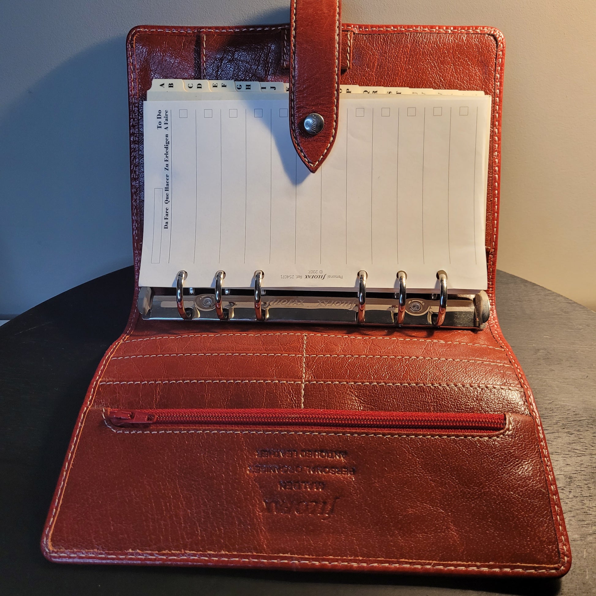 Geöffneter brauner Leder-Organizer von Filofax im A5-Format, mit Ringbuchmechanismus, alphabetischen Registerkarten, Reißverschlussfach und Kartenfächern. Perfekt für stilvolle Organisation und Aufgabenverwaltung.
