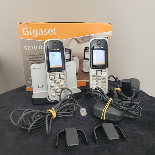 as Gigaset Siemens S670 Duo Eco Dect Titanium Intuitive Eleganz Schnurlostelefon liegt auf einem dunklen Hintergrund. Die beiden Mobilteile sind nebeneinander positioniert und zeigen ihr elegantes Titanium-Finish sowie das intuitive LCD-Display. Das Haupttelefon ist aktiviert, und die Bedienelemente sind klar sichtbar. Ein zuverlässiges DECT-Telefon mit moderner Technologie und stilvollem Design – perfekt für eine hochwertige Kommunikation!