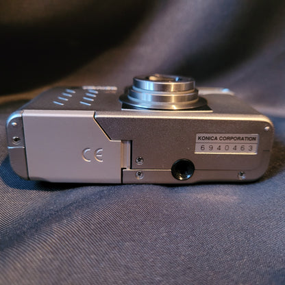 Untere Seite der Konica Revio Kamera mit Batteriefach, CE-Kennzeichnung, Stativgewinde und Seriennummer 6940463. Vintage Kamera mit silbernem Gehäuse.