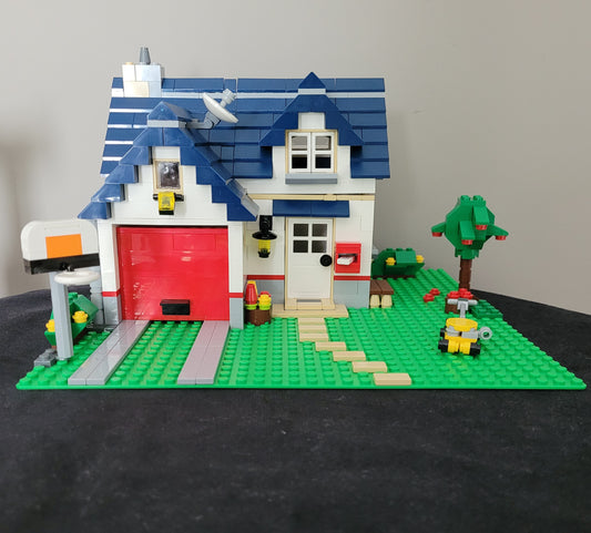 Das LEGO Creator Modell 5891 - Haus mit Garage – detailreiches Einfamilienhaus mit blauen Dachziegeln, rotem Garagentor und liebevoll gestalteter Umgebung inklusive Baum, Briefkasten und Rasenmäher. Perfektes Set für LEGO-Fans und Sammler! EAN: 5702014600546.