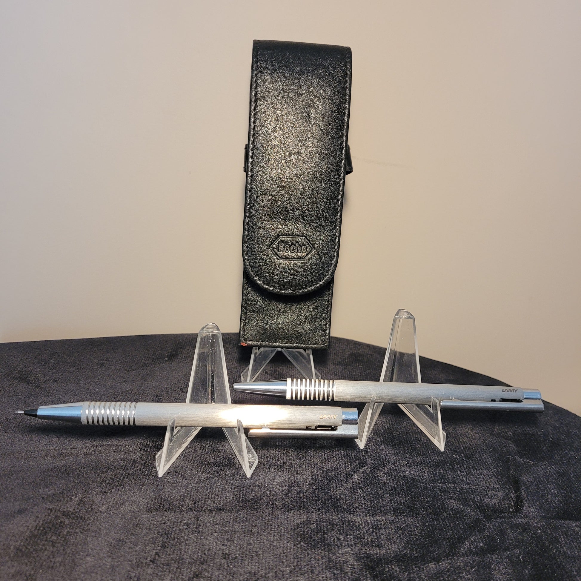 Ein hochwertiges Lamy Roche Set bestehend aus einem schwarzen Lederetui, einem silbernen Kugelschreiber und einem Druckbleistift, auf dunklem Hintergrund platziert. Perfekt für stilbewusste Schreiber und Sammler.