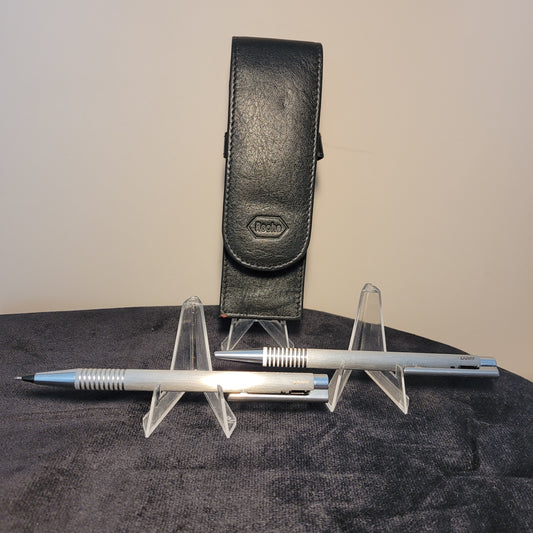 Ein hochwertiges Lamy Roche Set bestehend aus einem schwarzen Lederetui, einem silbernen Kugelschreiber und einem Druckbleistift, auf dunklem Hintergrund platziert. Perfekt für stilbewusste Schreiber und Sammler.