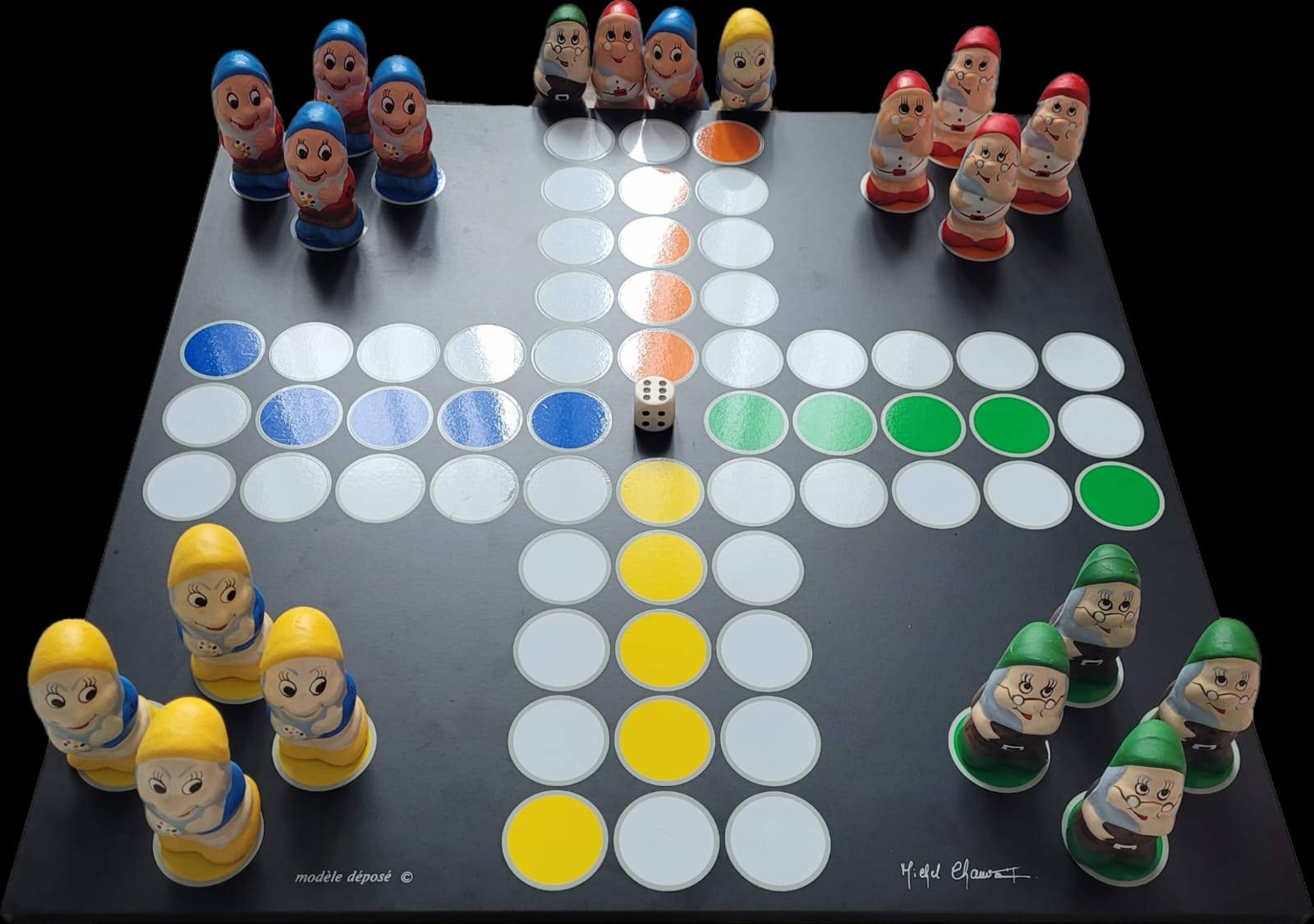 Das Bild zeigt die Vorderseite des Gesellschaftsspiels "Decoplay", gestaltet von Michel Chauvaux, mit Zwergfiguren von Deco Play. Das Spielbrett ist auf einem schwarzen Untergrund platziert, und die detailreich gestalteten Zwergfiguren stehen auf ihren jeweiligen Positionen. Die Signatur von Michel Chauvaux ist sichtbar und verleiht dem Design eine besondere Authentizität.