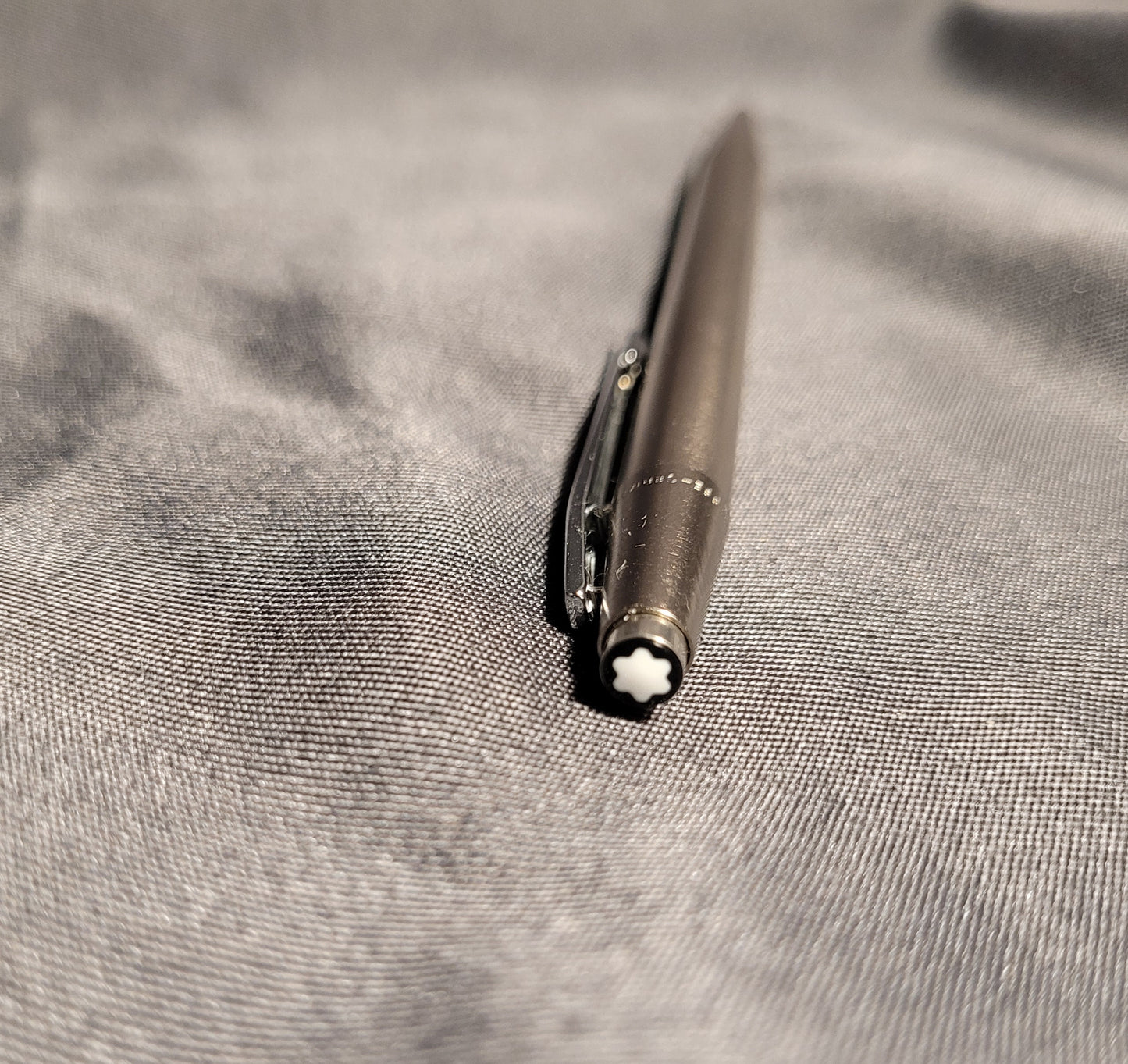 Nahaufnahme des Drückers eines Vintage Montblanc Noblesse Kugelschreibers. Zu sehen ist der charakteristische weiße Montblanc-Stern (Snowcap) auf schwarzem Grund sowie der präzise gearbeitete Metallclip des Slimline-Modells aus den 70er/80er Jahren.