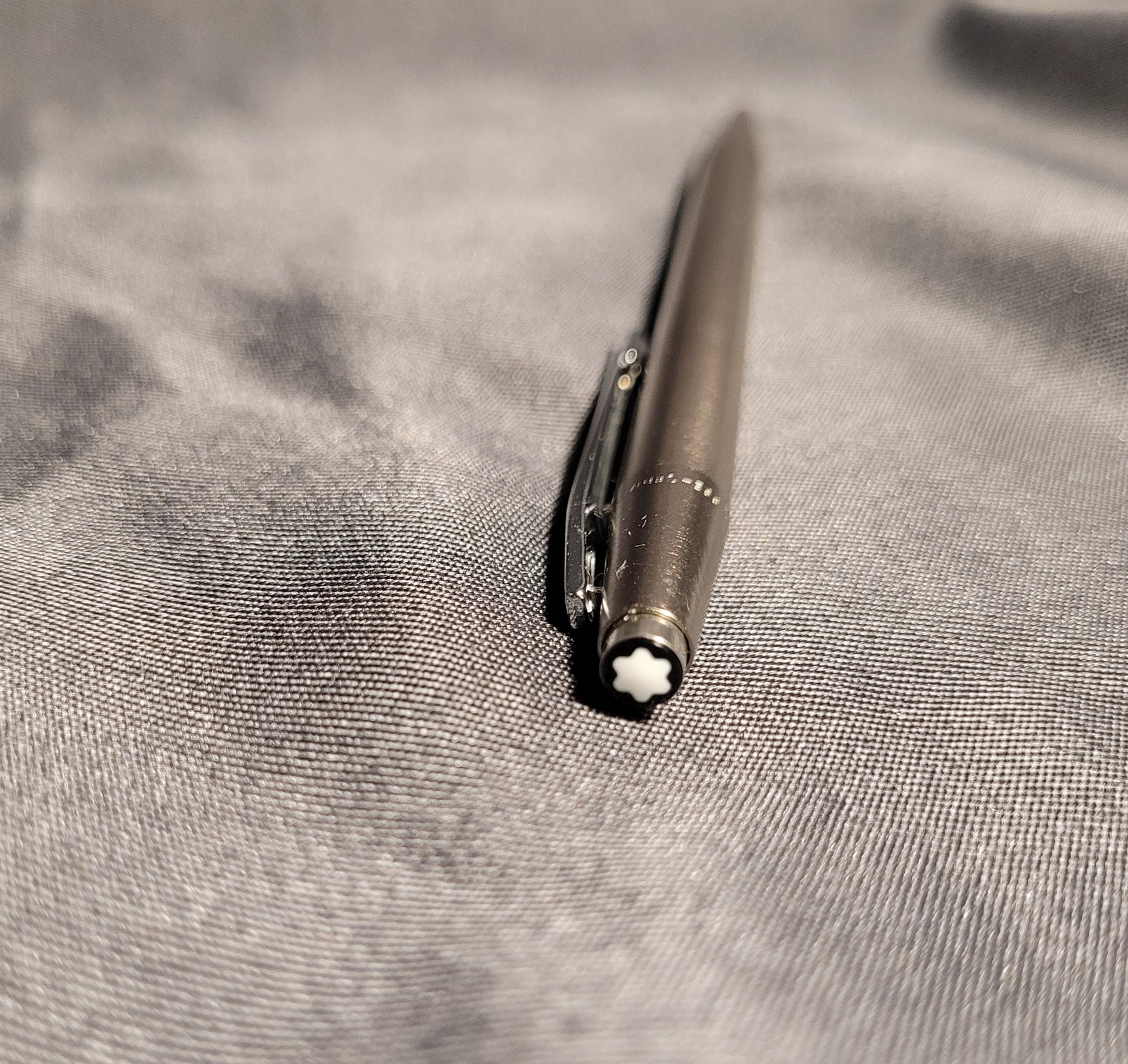 Nahaufnahme des Drückers eines Vintage Montblanc Noblesse Kugelschreibers. Zu sehen ist der charakteristische weiße Montblanc-Stern (Snowcap) auf schwarzem Grund sowie der präzise gearbeitete Metallclip des Slimline-Modells aus den 70er/80er Jahren.