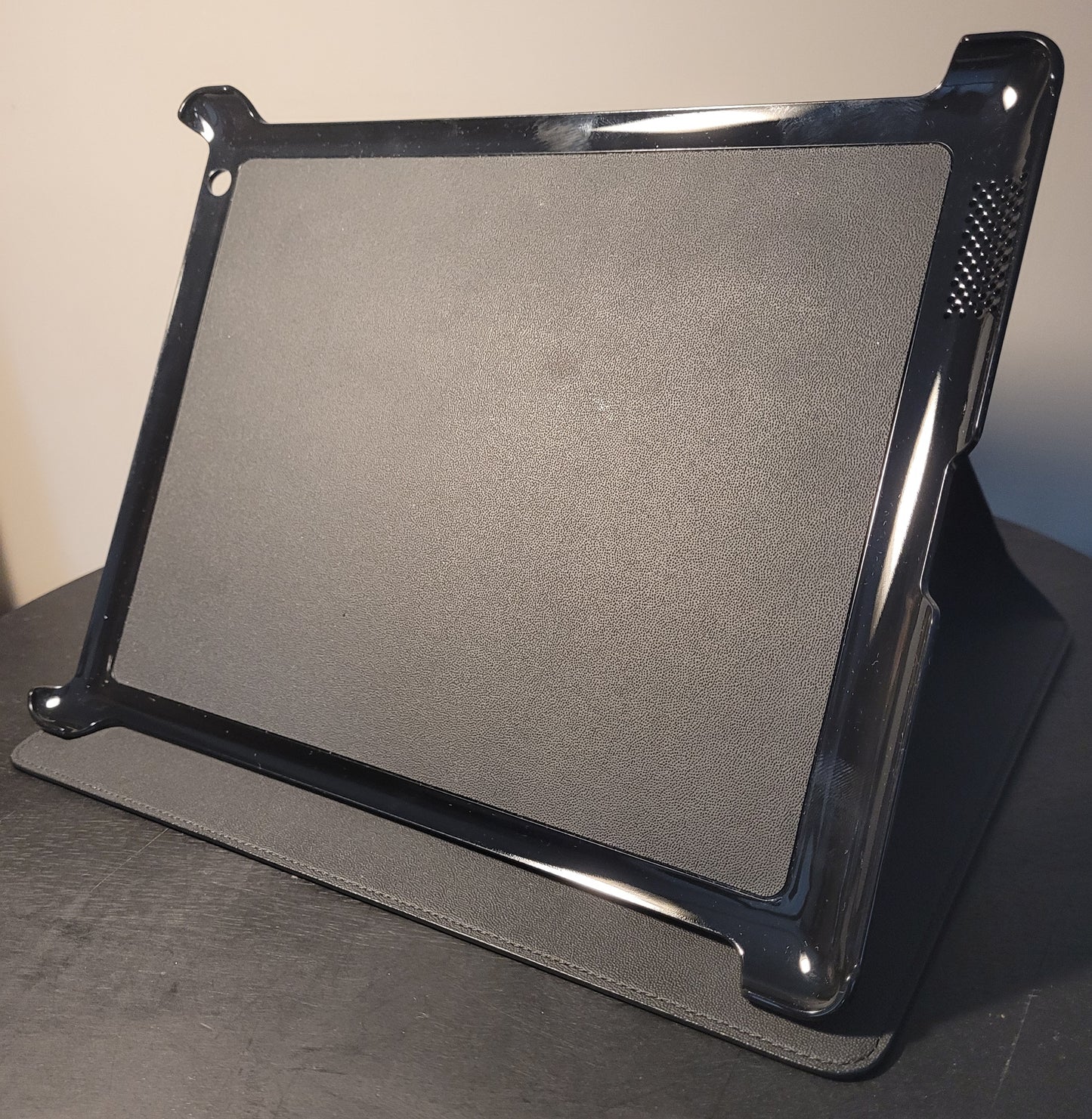 Montblanc Tablet Halter für iPad 3 aus schwarzem Leder mit strukturierter Rückseite, glänzender Kunststoffumrandung und Lüftungsschlitzen, auf einem Tisch stehend.