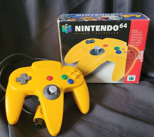 Nintendo 64 – N64 – Gelber Controller/Joystick Model NUS-005A mit Originalverpackung (OVP). Der Controller zeigt das klassische dreizackige Design mit grauem Analogstick, rotem Startknopf, Steuerkreuz sowie bunten A-, B- und C-Tasten. Die OVP trägt das Nintendo 64 Logo und die Aufschrift „Gelber Controller“ mit Abbildung des Controllers. Retro/Vintage Zubehör für die N64 Konsole.